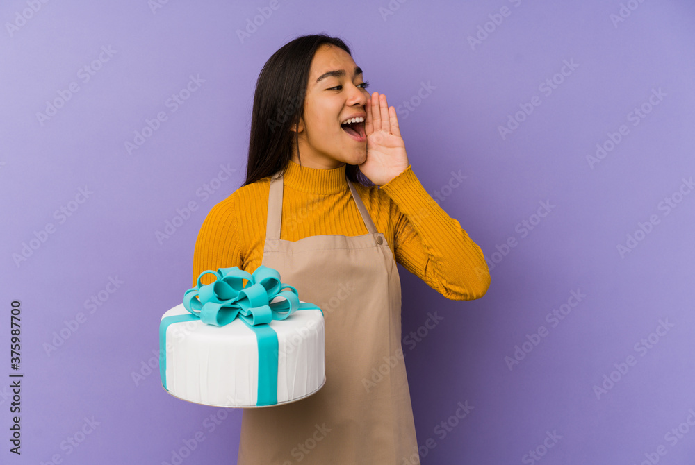 Young asian woman holding a cake isolated shouting and holding palm near opened mouth. Young asian woman holding a cake isolated shouting and holding palm near opened mouth.
