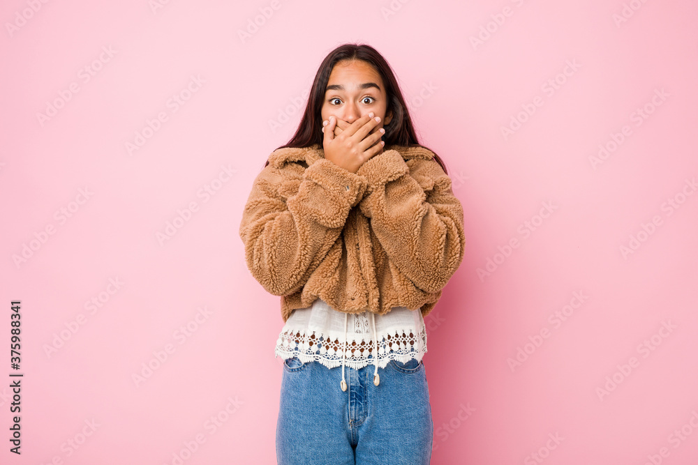 Young mixed race indian woman wearing a short sheepskin coatshocked covering mouth with hands. Young mixed race indian woman wearing a short sheepskin coatshocked covering mouth with hands.