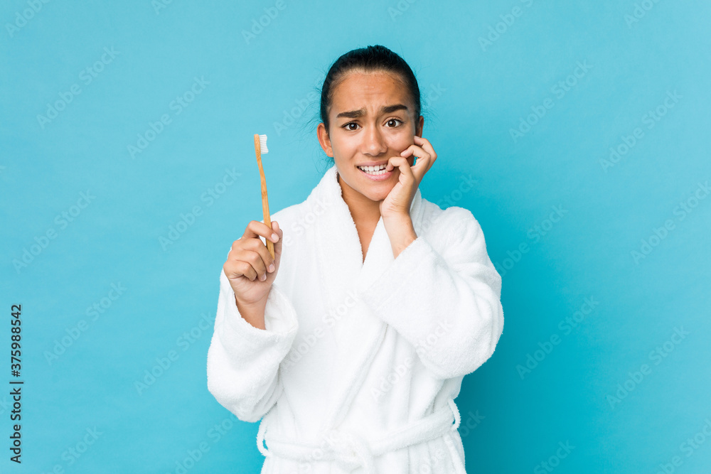 Young mixed race indian holding a toothbrush biting fingernails, nervous and very anxious. Young mixed race indian holding a toothbrush biting fingernails, nervous and very anxious.