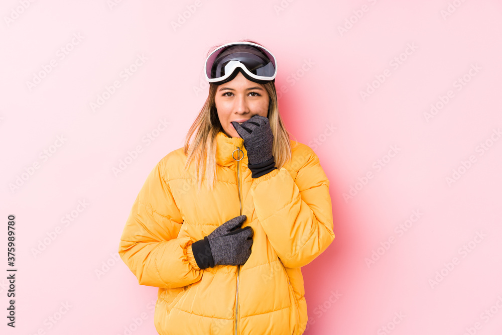 Young caucasian woman wearing a ski clothes in a pink background biting fingernails, nervous and very anxious.