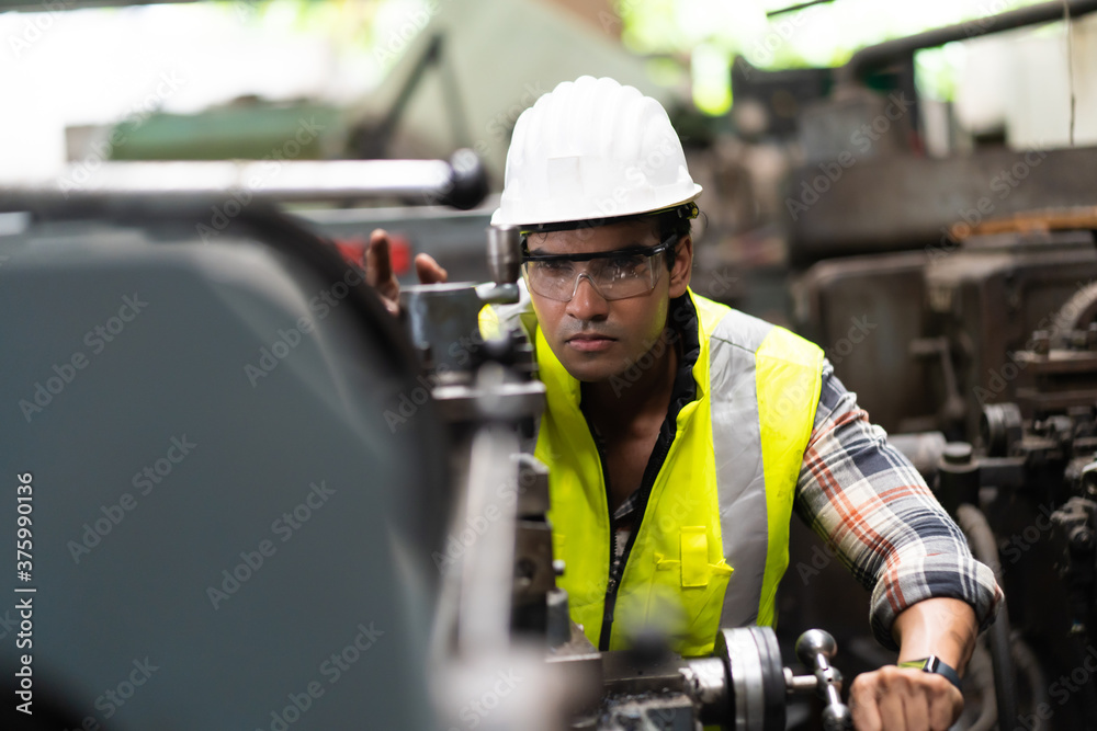Man at work. Mechanical Engineer man in Hard Hat Wearing Safety Jacket working in Heavy Industry Manufacturing Facility. Professional Engineer Operating lathe Machinery Man at work. Mechanical Engineer man in Hard Hat Wearing Safety Jacket working in Heavy Industry Manufacturing Facility. Professional Engineer Operating lathe Machinery