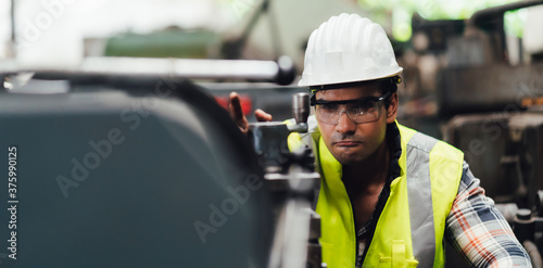 Man at work. Mechanical Engineer man in Hard Hat Wearing Safety Jacket working in Heavy Industry Manufacturing Facility. Professional Engineer Operating lathe Machinery