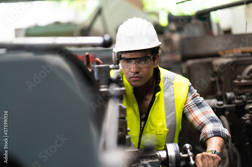 Man at work. Mechanical Engineer man in Hard Hat Wearing Safety Jacket working in Heavy Industry Manufacturing Facility. Professional Engineer Operating lathe Machinery