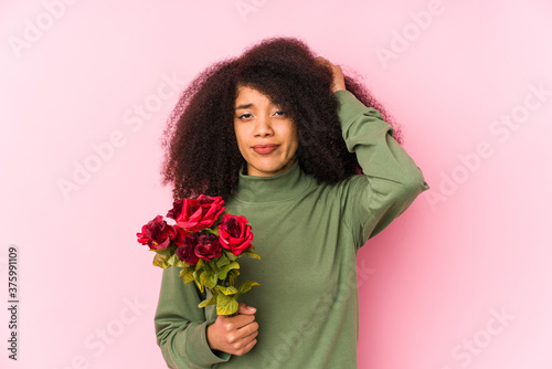 Young afro woman holding a roses isolated Young afro woman holding a rosesbeing shocked, she has remembered important meeting.