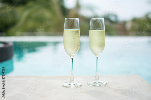 Two sparkling champagne glasses or prosecco near swimming pool. Summer travel, vacation, holiday and weekend concept