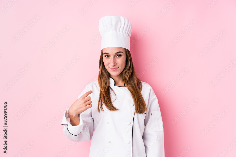 Young caucasian chef woman isolated pointing with finger at you as if inviting come closer. Young caucasian chef woman isolated pointing with finger at you as if inviting come closer.