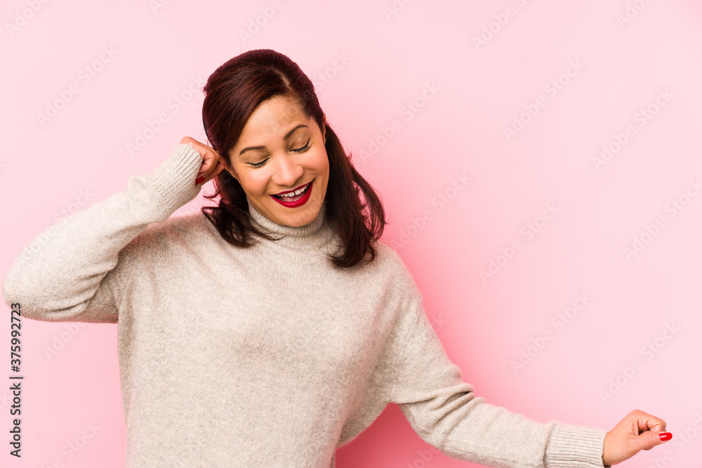 Middle age latin woman isolated on a pink background dancing and having fun. Middle age latin woman isolated on a pink background dancing and having fun.