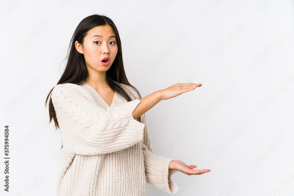 Young chinese woman isolated shocked and amazed holding a copy space between hands. Young chinese woman isolated shocked and amazed holding a copy space between hands.