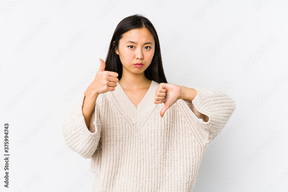 Young chinese woman isolated showing thumbs up and thumbs down, difficult choose concept Young chinese woman isolated showing thumbs up and thumbs down, difficult choose concept