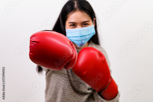 Asian beautiful happy young woman wearing mask protection and boxing gloves her get ready for Coronavirus fighting against, with copy space © PK Studio