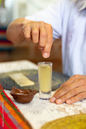 Close up of the hand of an anonymous man adding salt to a shot of tequila