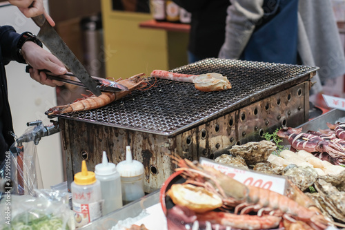 hand of chef grilling king crab legs on charcoal grill at japan market photo