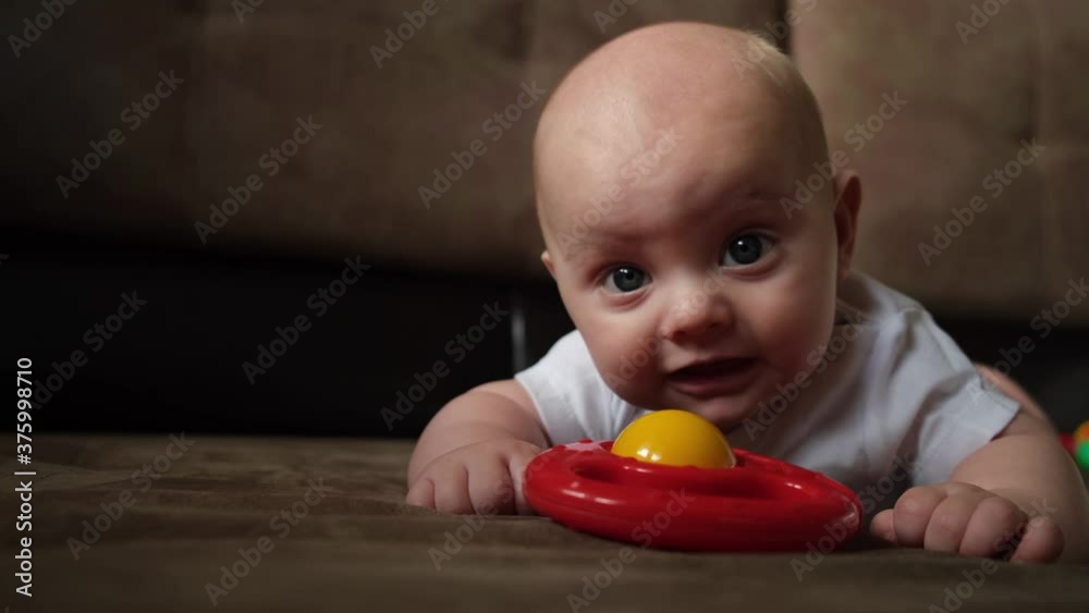 Infant baby boy lying on sofa with rattle toy. Infant baby boy lying on sofa with rattle toy.