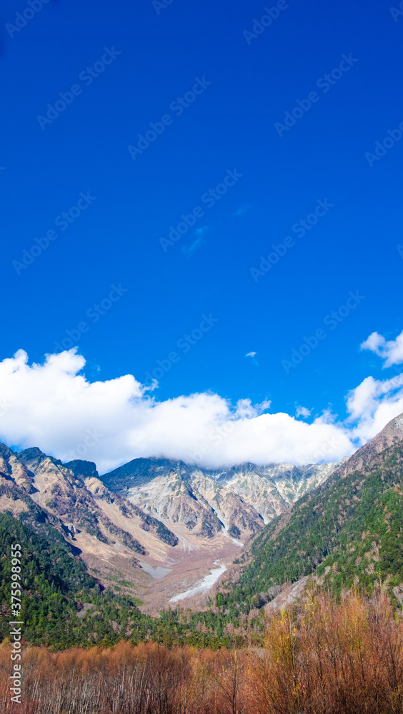 Scenic Landscape layer mountains range with cloudy blue sky background in fall autumn season at kamikochi national park in Japan