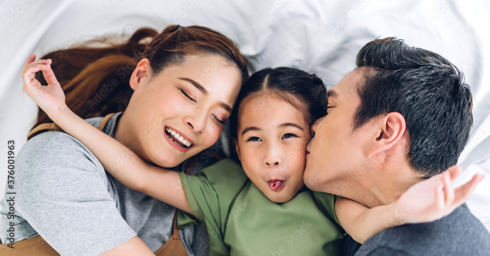 Top view of portrait enjoy happy smiling love asian family father and mother with young parents little asian girl looking at camera in moments good time lying on the floor at home Top view of portrait enjoy happy smiling love asian family father and mother with young parents little asian girl looking at camera in moments good time lying on the floor at home