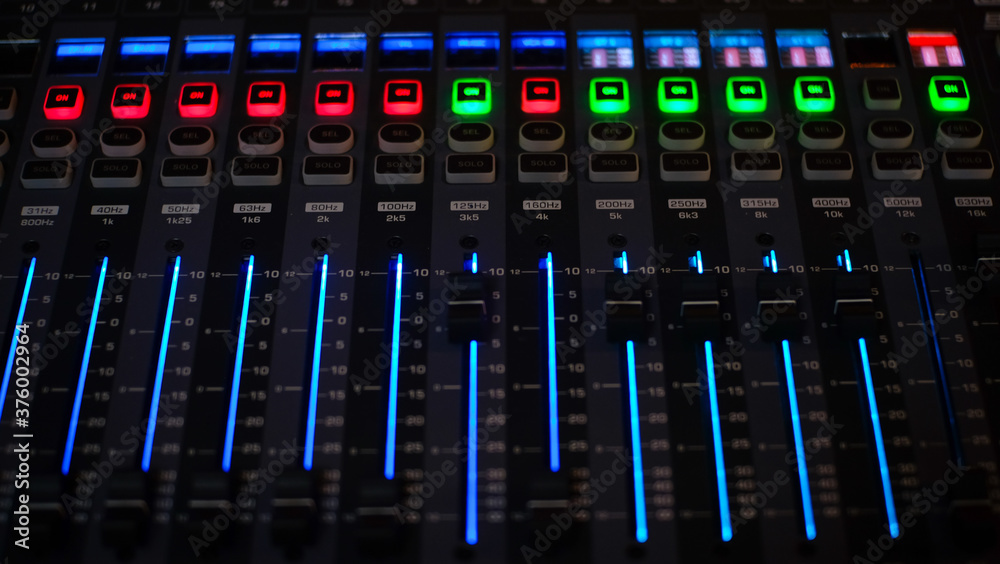 Digital Music mixer with buttons and sliders control panel in a recording Studio