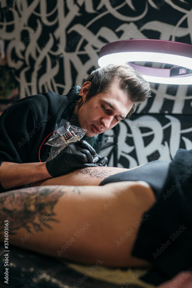 
tattoo artist fills the leg with a tattoo