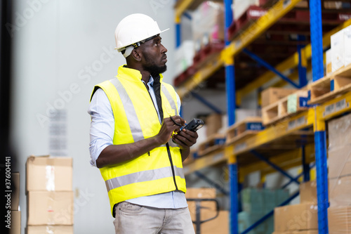 middle aged African American warehouse worker preparing a shipment in large warehouse distribution centre