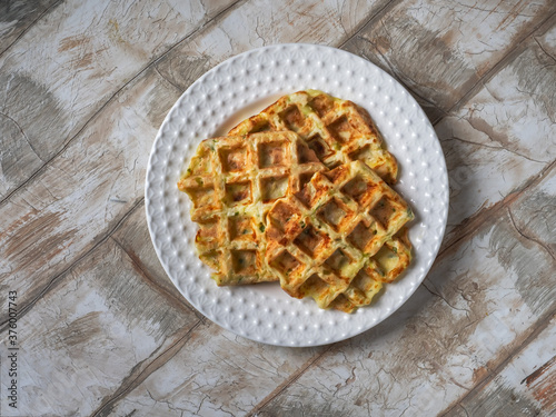 Zucchini waffles on a white plate on a wooden decorative table