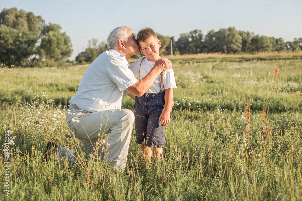 Happy child with Grandfather playing at the meadow. Grandpa retiree. Retirement parent