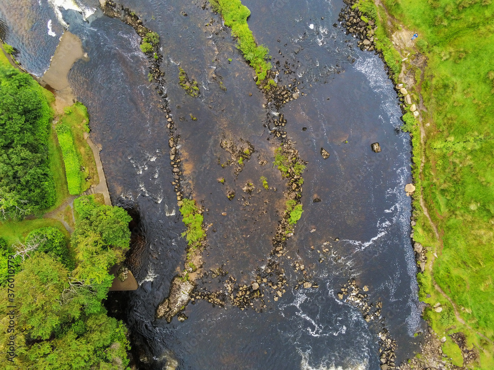 Small river flows by a green fields, West of Ireland, Aerial top down view.
