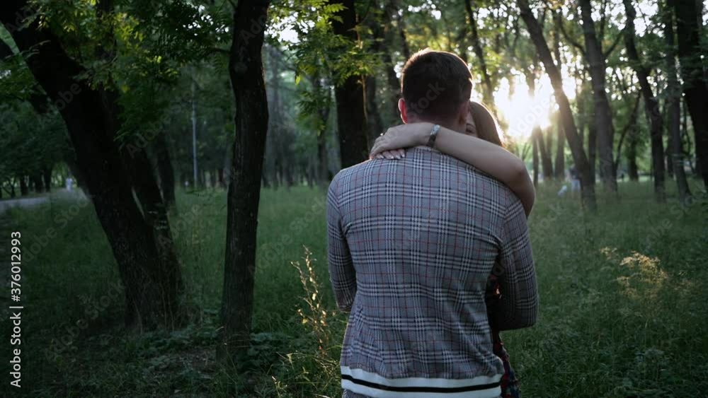 Happy young family couple hug and kiss in a summer Park at sunset Happy young family couple hug and kiss in a summer Park at sunset