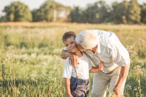 family, generation, communication and people concept - happy grandfather kisses his grandson  at summer meadow © Maria