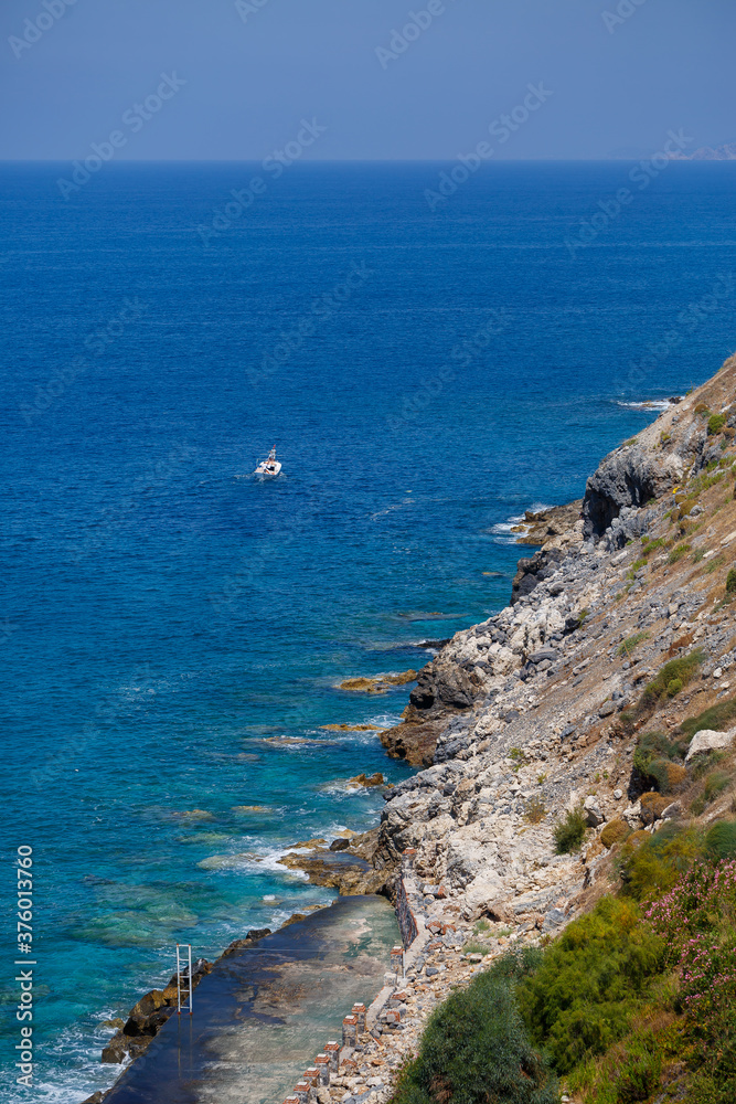 A view of the Mediterranean coast with waves of azure water. Summer seascape. Seaside in sunny weather. Beautiful sea view