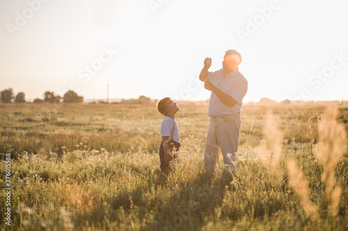 Happy senior man Grandfather with cute little boy grandson playing in field. Happy child with Grandfather playing outdoors