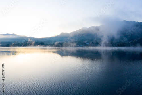 Lovely autumnal landscape with fog over the lake.