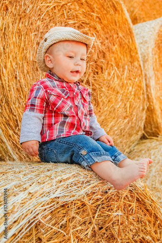 a Baby girl on a haystack happy on the field. Background with children a joyful childhood.