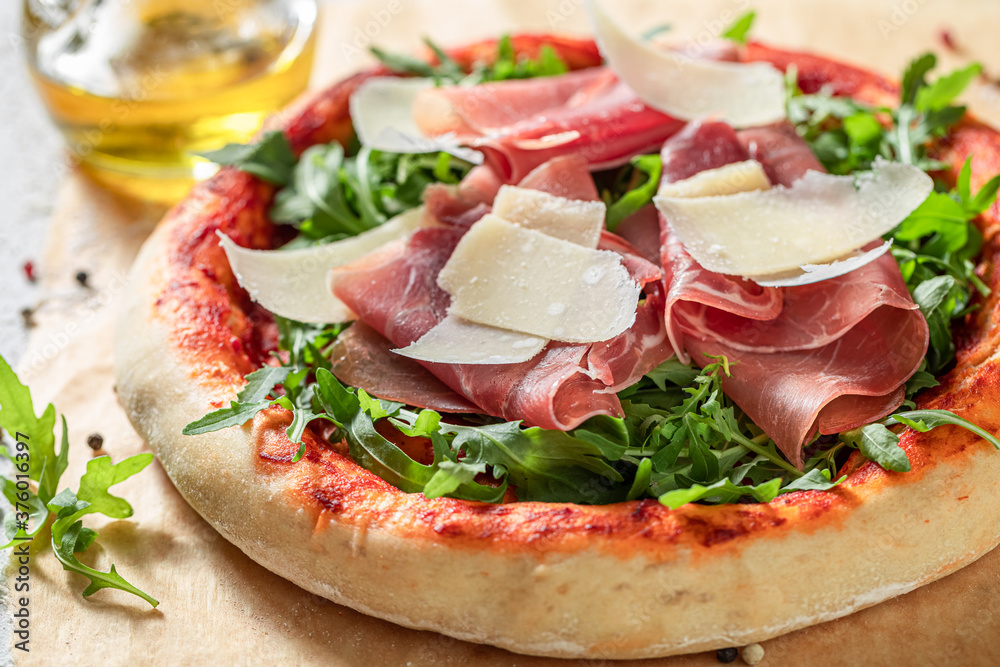 Closeup of pizza Parma with prosciutto, arugula and parmesan Closeup of pizza Parma with prosciutto, arugula and parmesan