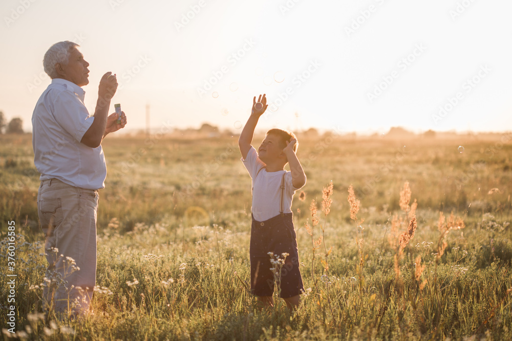 Happy senior man Grandfather with cute little boy grandson playing in field. Happy child with Grandfather playing outdoors Happy senior man Grandfather with cute little boy grandson playing in field. Happy child with Grandfather playing outdoors