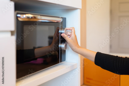 Hands woman using microwave oven in home kitchen