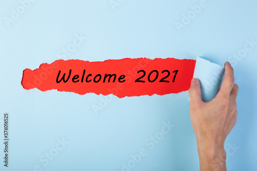 Hand tearing color paper with word Welcome Year 2021