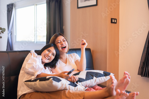 Happy couple asian woman watching TV feeling having fun together at home photo