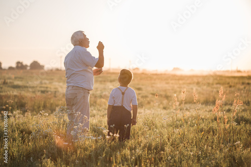 Happy senior man Grandfather with cute little boy grandson playing in field. Happy child with Grandfather playing outdoors © Maria