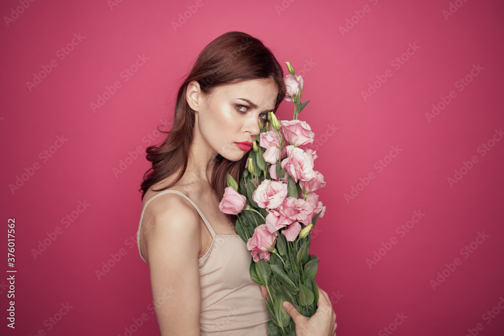beautiful woman with a bouquet of flowers on a pink background in a light dress makeup model