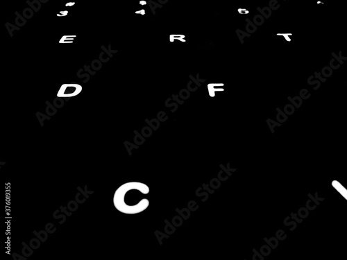 Creative Fine Art Image Illustration of White Glowing English Alphabet Letters On Dark Black Background Copy Space For Text. Modern abstract front style in computer keyboard typewriter sequence order.