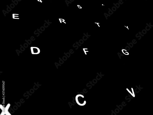 Creative Fine Art Image Illustration of White Glowing English Alphabet Letters On Dark Black Background Copy Space For Text. Modern abstract front style in computer keyboard typewriter sequence order.