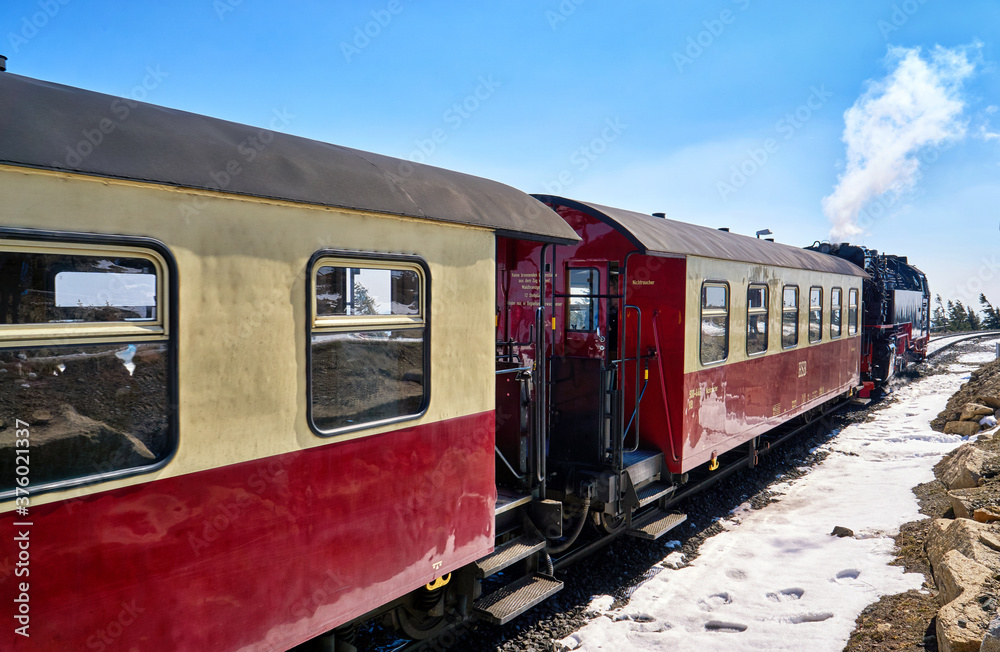 Fototapeta premium Steam locomotive with passenger wagons in winter on the Brocken in the Harz Mountains with snow. Germany