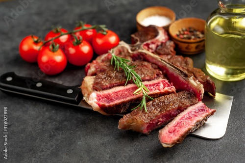 grill t-bone steak with ingredients on a meat knife on stone background