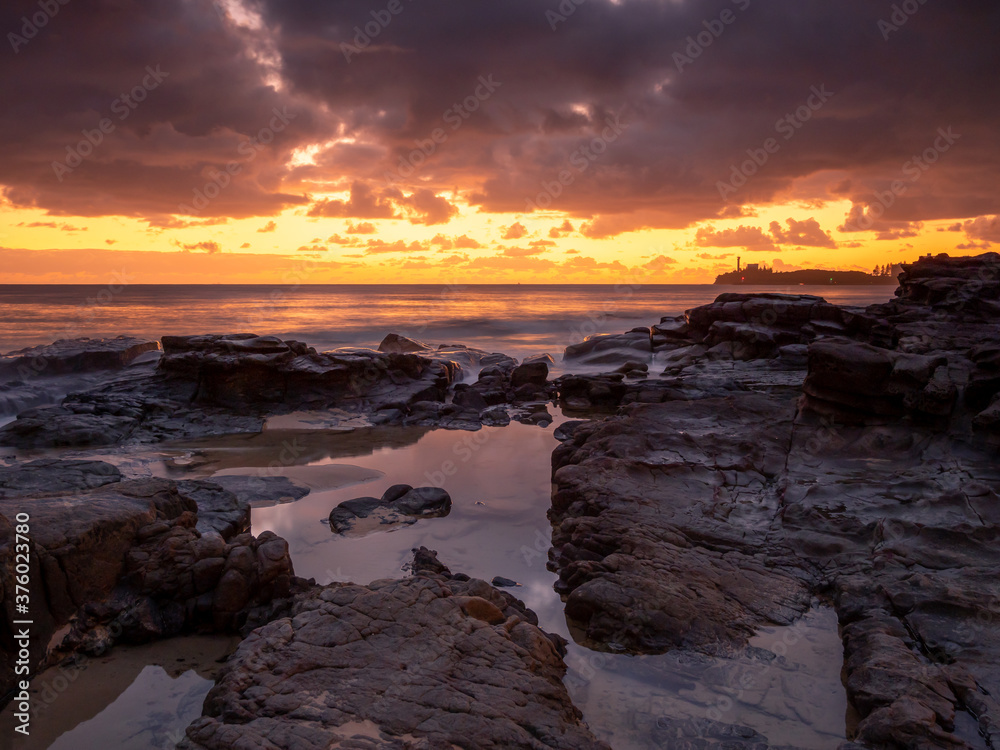 Golden Seaside Sunrise with Rockpool Reflections and Crashing Waves Golden Seaside Sunrise with Rockpool Reflections and Crashing Waves