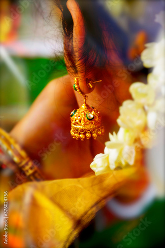 Indian Traditional Yellow Gold Zumka Studded with Polki Stone Earring Wear by Indian Lady Dress up with Saree in Holly Pooja Closeup View photo