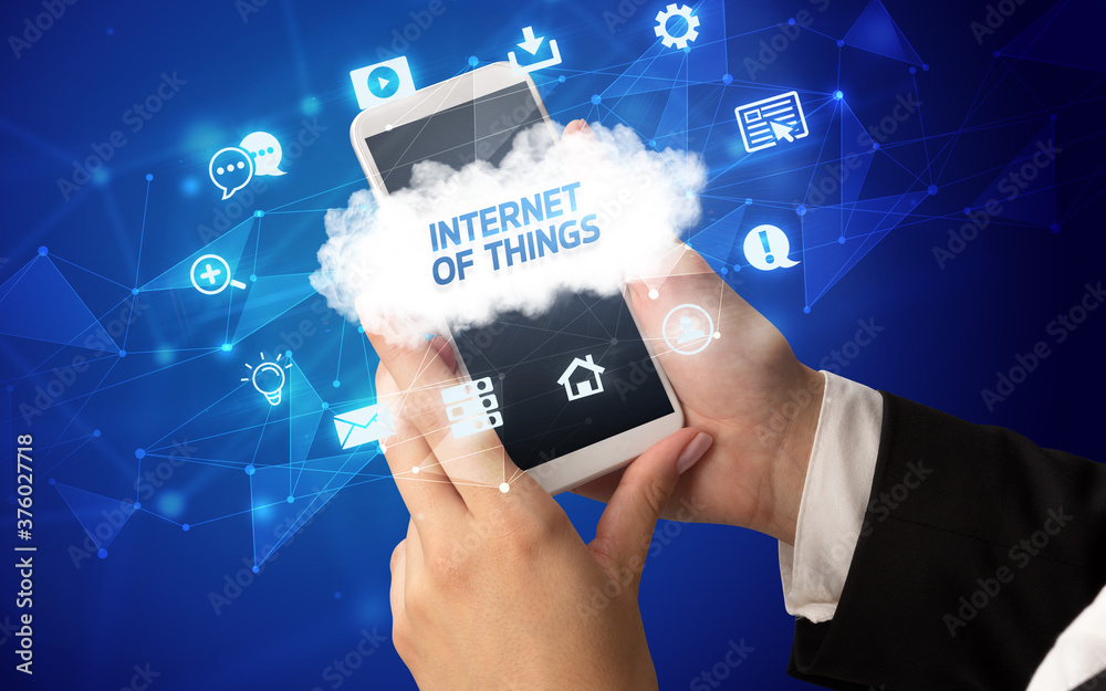 Female hand holding smartphone with INTERNET OF THINGS inscription, cloud technology concept Female hand holding smartphone with INTERNET OF THINGS inscription, cloud technology concept