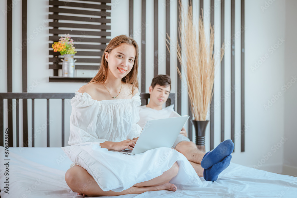 Portrait happy couple lady stayed on bed to search information on web with notebook in her bedroom Portrait happy couple lady stayed on bed to search information on web with notebook in her bedroom