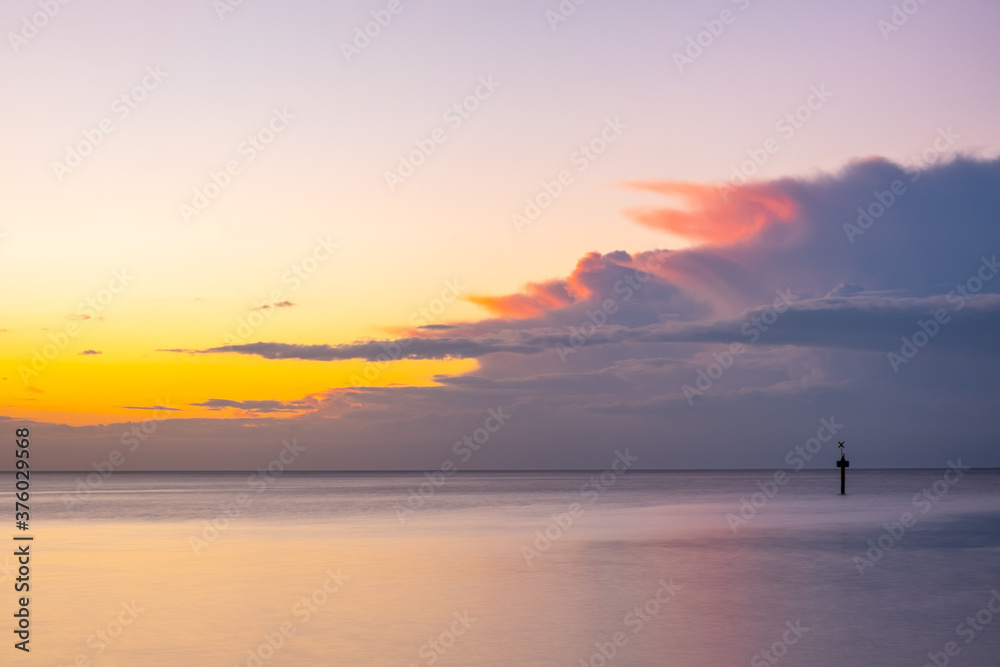 Nothing but skies and silky smooth water at glowing ocean sunset with copy space