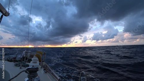 Sailing yacht on the open sea. Dramatic twilight sky over the waves. Slow motion.