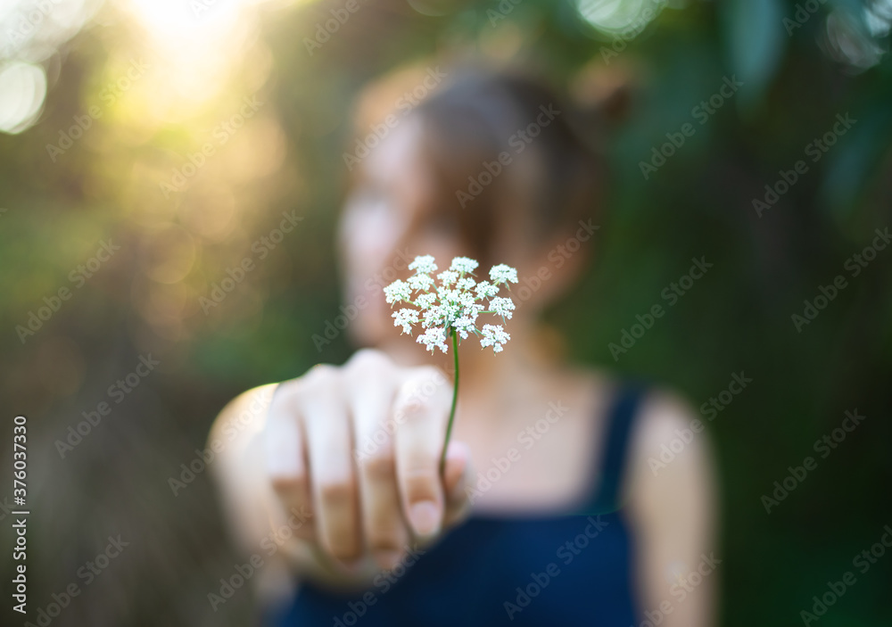 White flower in hands of pretty young girl. Selective focus White flower in hands of pretty young girl. Selective focus