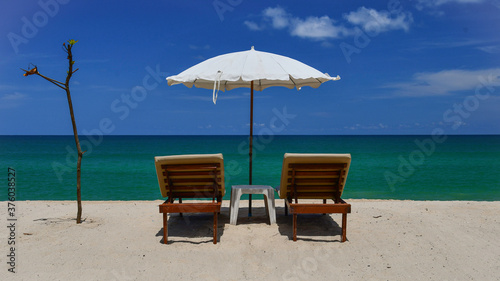 Tropical beach, sunloungers and white parasol © Angela